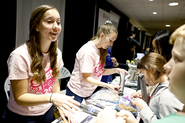 Student volunteers helping young people with a STEM Fest project.