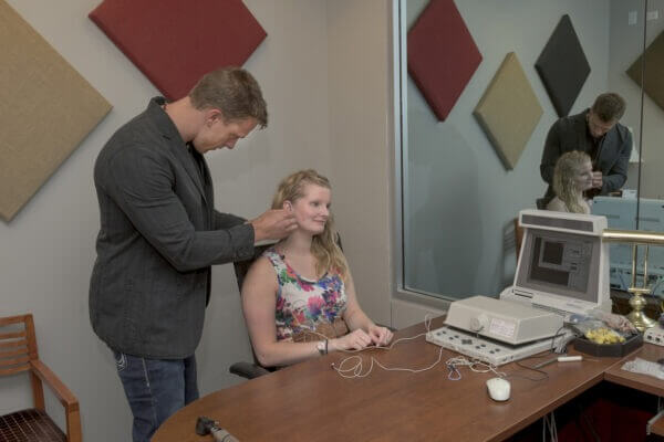Researcher using audiology equipment on a woman.
