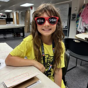 A kid in yellow t-shirt wearing NIU Steam glasses