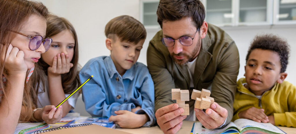 Man teacher with kids during chemistry lesson in school classroom, studying new topic.