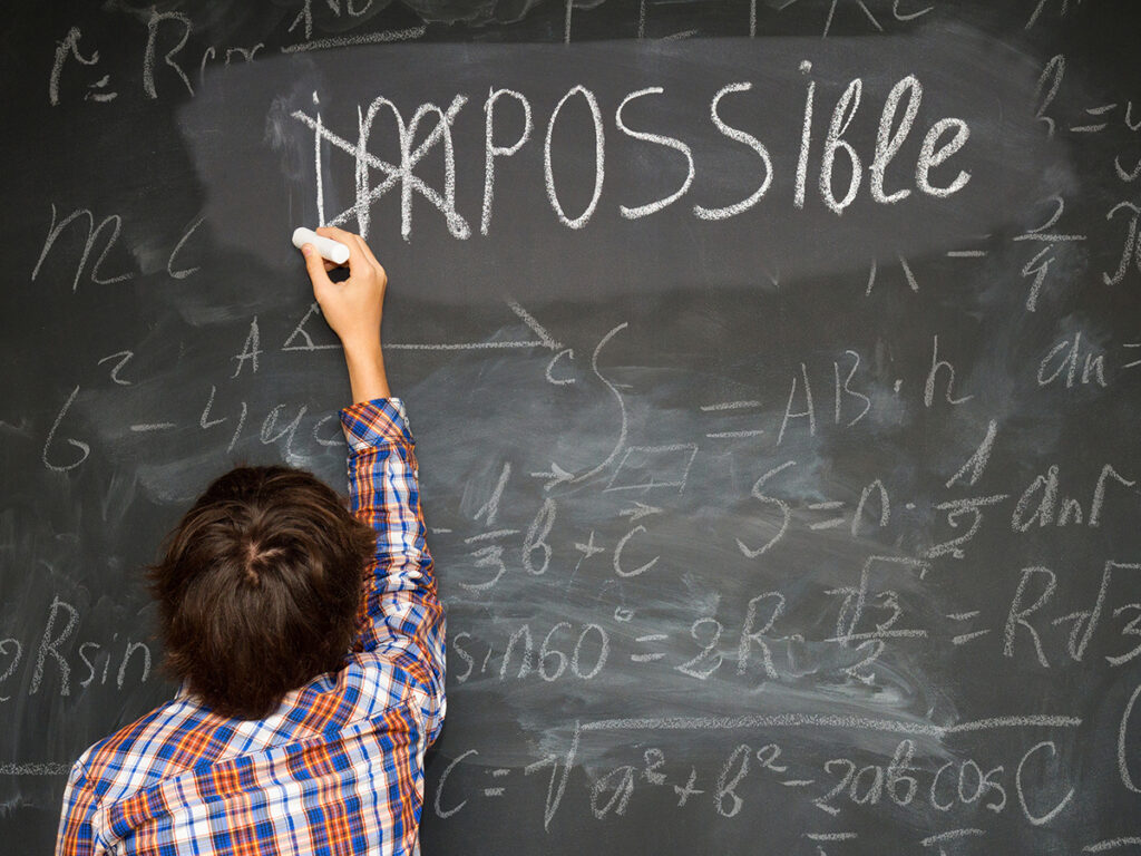 boy putting a cross over impossible on blackboard with math calculations