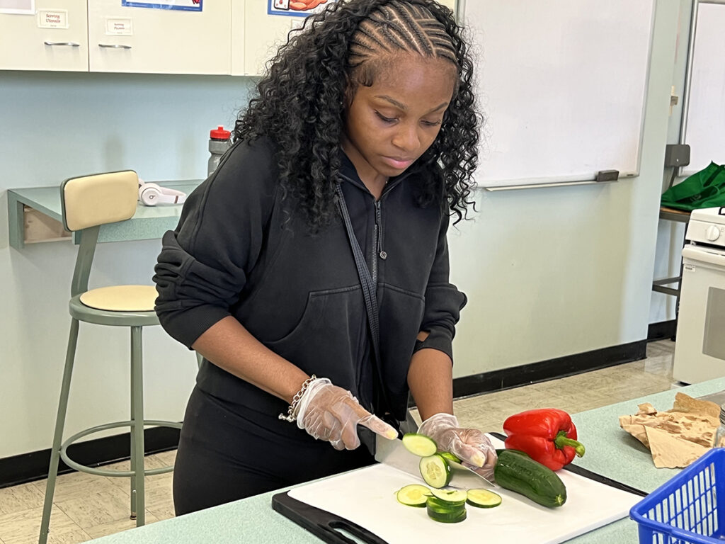 An African American girl cuts vegetables