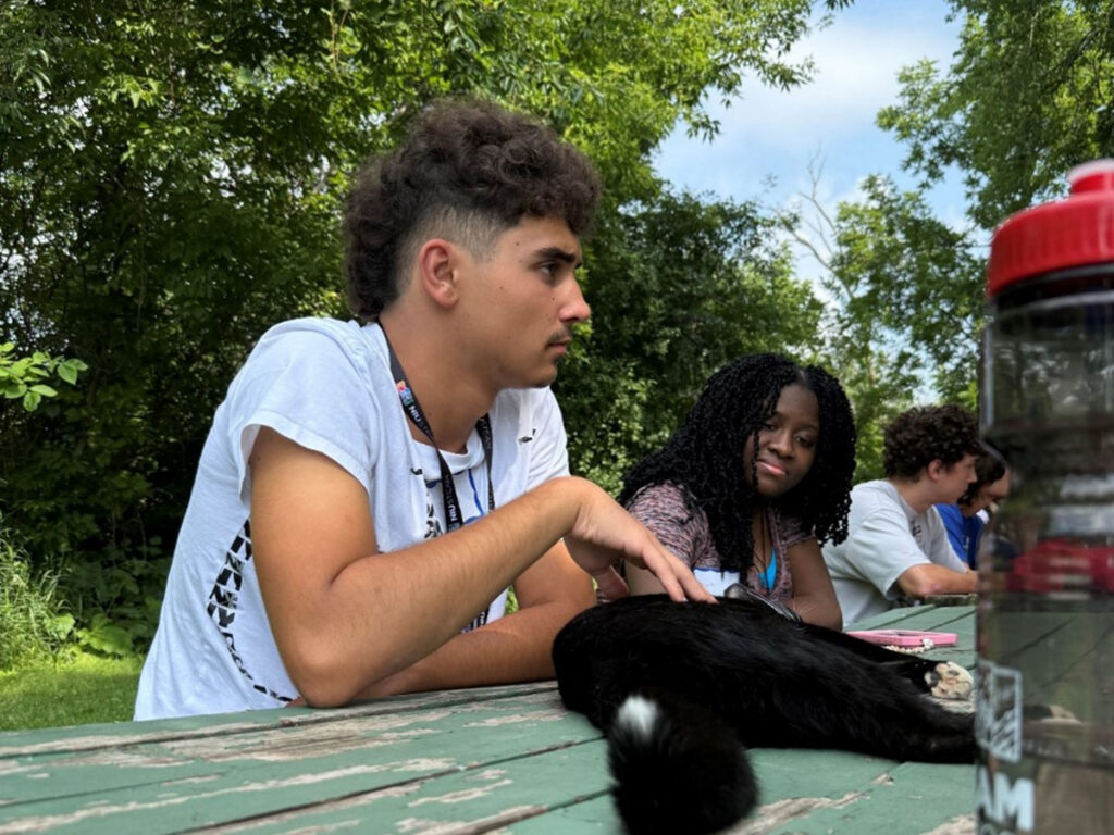 A young man petting a cat at summer camp